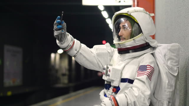 Un-hombre-vestido-de-astronauta-utiliza-el-smartphone-para-llamar-y-enviar-mensajes.-Las-sonrisas-de-astronauta-mirando-el-teléfono-en-la-mano.