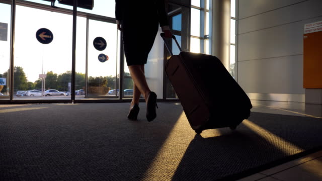 Business-lady-going-from-airport-with-her-luggage.-Woman-in-heels-walking-with-her-suitcase-from-terminal-to-city-street.-Girl-stepping-and-rolling-bag-on-wheels.-Trip-concept.-Slow-motion-Close-up