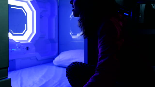 Woman-examines-the-Sleepbox-with-neon-lights,-a-space-capsule-container-for-sleeping-at-the-airport