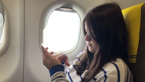 Teenager-girl-uses-smartphone-on-plane