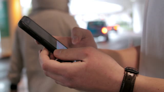 Aufnahme-der-Hände-mit-Smartphone-app-Aufruf-Fahrt-Anteil-Auto-am-Flughafen-hautnah