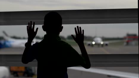 Junge-steht-in-der-Nähe-der-Fenster-am-Flughafen-und-schaut-auf-die-Flugzeuge-der-Junge-träumt-davon,-pilot