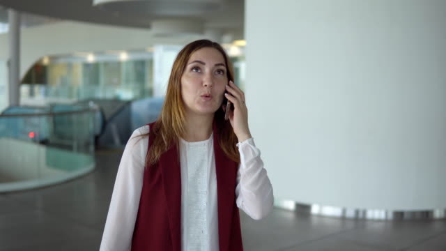 Positiven-junges-Mädchen-in-eleganten-Kleidern-spricht-auf-Smartphone-am-Flughafen