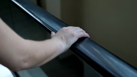 woman-rides-on-an-escalator-holding-onto-a-railing