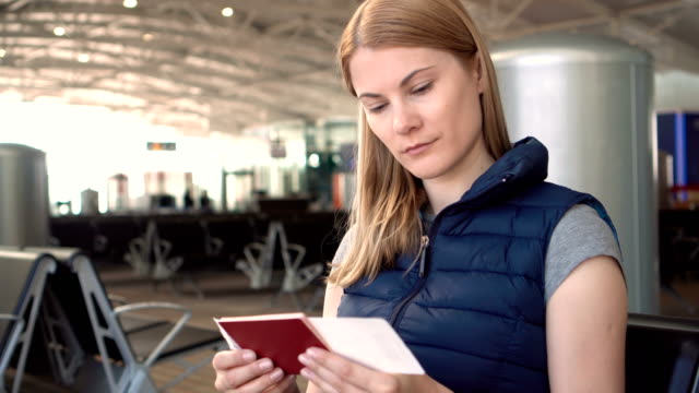 Beautiful-young-woman-at-the-airport.-Waiting-for-her-flight.-Checking-passport-and-boarding-pass