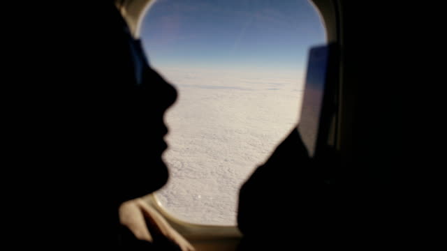Closeup-Silhouette-Frau-sitzt-in-der-Nähe-von-Flugzeugfenster-mit-Handy-während-des-Fluges