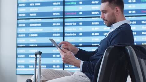 Mann-mit-Tablet-beim-Boarding-warten-am-Abflug-Lounge-am-Flughafen.