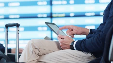 Man-using-Tablet-while-Waiting-Boarding-at-Departure-Lounge-at-the-Airport.