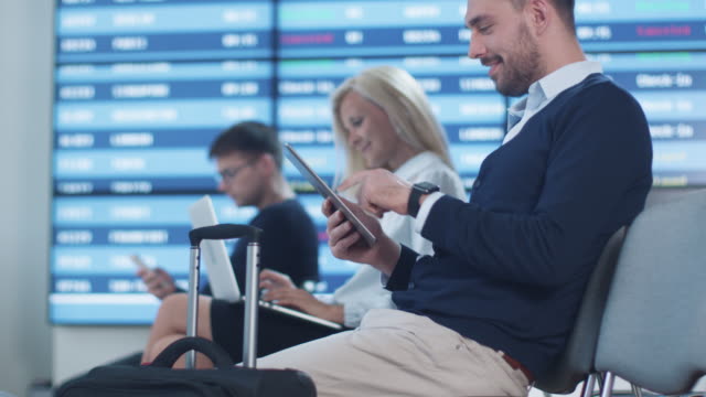 Mann-mit-Tablet-beim-Boarding-warten-am-Abflug-Lounge-am-Flughafen.