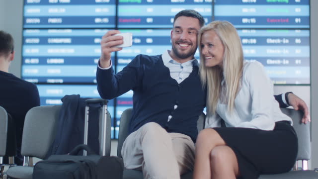 Mann-und-Frau-machen-Selfie-Bilder-mit-Telefon,-während-das-Warten-in-der-Abfluglounge-am-Flughafen.