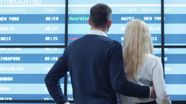 Kaukasischen-Ethnicity-Mann-und-Frau-betrachten-Informationstafel-am-Flughafen.