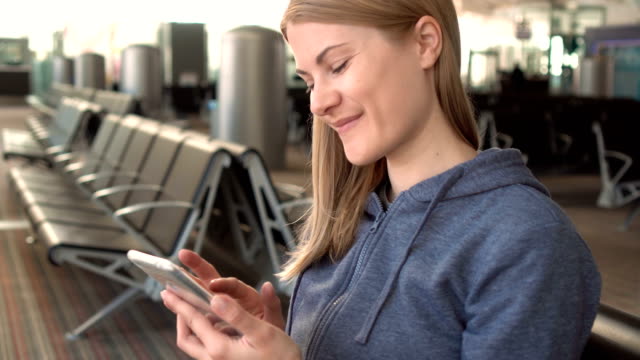 Beautiful-woman-using-smartphone-in-airport.-Browsing-internet,-communicating-with-her-friends