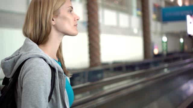 Beautiful-attractive-woman-in-airport-terminal.-Waiting-for-flight.-Using-travolator,-looking-around