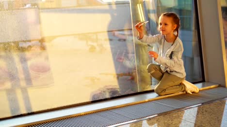 Entzückende-kleine-Mädchen-spielen-mit-kleinen-Modell-Flugzeug-Spielzeug-im-Flughafen-in-der-Nähe-großer-Fenster.-Konzept-des-Fliegens-und-Flugzeug.