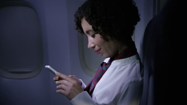 Auxiliar-de-vuelo-utilizando-el-teléfono-celular-en-la-noche