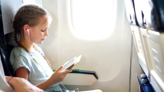 Adorable-little-girl-traveling-by-an-airplane.-Cute-kid-with-laptop-near-window-in-aircraft