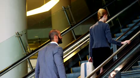 Businessman-and-woman-climbing-staircase-with-luggage