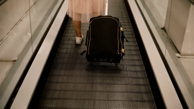 Vista-de-primer-plano-de-mujer-joven-con-la-situación-de-la-maleta-en-la-escalera-mecánica-en-el-aeropuerto.-Mujer-hipster-lista-para-ir-a-viaje