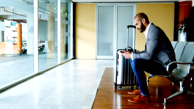 Businessman-texting-on-mobile-phone-at-airport