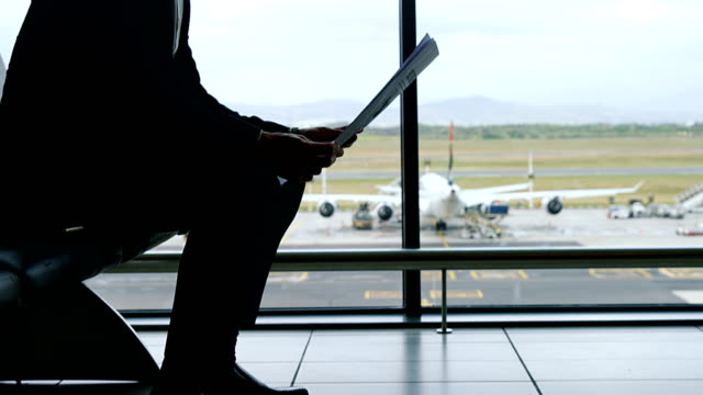 Geschäftsmann-am-Flughafen-sitzen-und-Zeitung-lesen