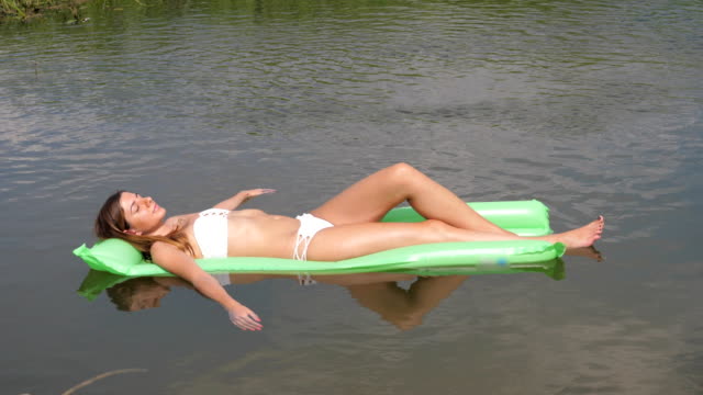 Closeup-junge-Frau-im-weißen-Badeanzug-Sonnenbaden-Handauflegen-Matratze-im-Wasser