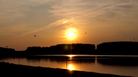 Luftballons-auf-dem-Hintergrund-der-untergehenden-Sonne-und-See