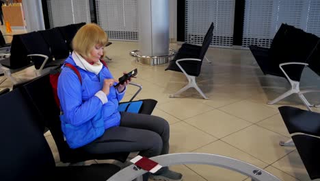 Die-Frau-am-Flughafen-warten-auf-Abfahrt-und-schreibt-in-einem-Smartphone.