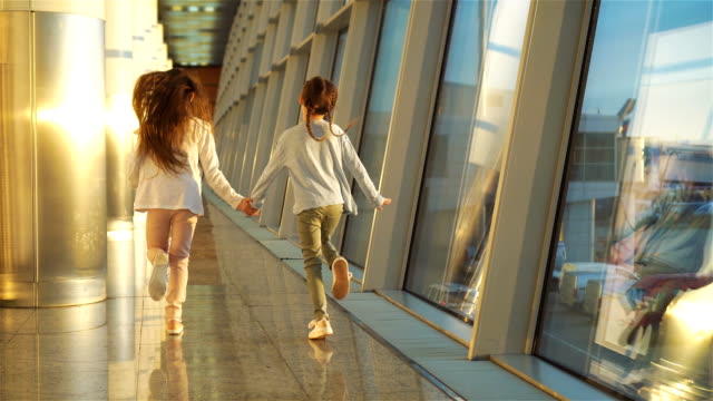 Little-adorable-girls-in-airport-waiting-for-boarding-near-big-window
