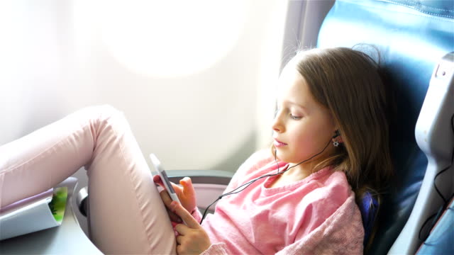 Entzückende-kleine-Mädchen-mit-dem-Flugzeug-reisen.-Süßes-Kind-mit-Laptop-in-der-Nähe-von-Fenster-im-Flugzeug