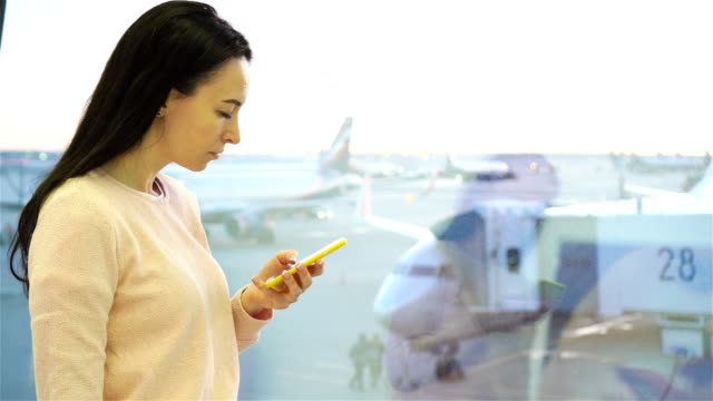 Porträt-der-jungen-Frau-mit-Smartphone-im-internationalen-Flughafen.-Flugreisenden-in-einer-Flughafenlounge-wartet-auf-Flug-Flugzeug
