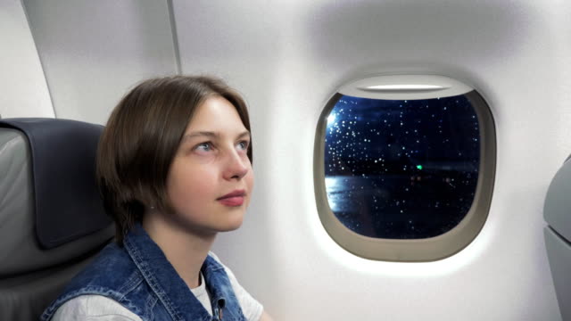 Junge-Frau-schaut-durch-Fenster-im-Flugzeug