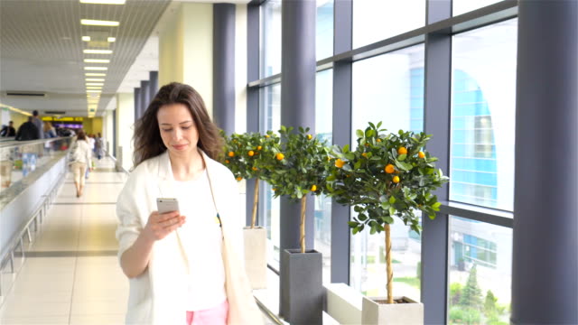 Junge-Frau-mit-Smartphone-im-internationalen-Flughafen.-Flugreisenden-in-einer-Flughafenlounge-wartet-auf-Flug-Flugzeug