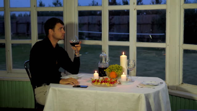 Mann-sitzt,-Tisch-am-Abend-trinkt-Rotwein,-sieht-entlang-der-Parteien-wartet