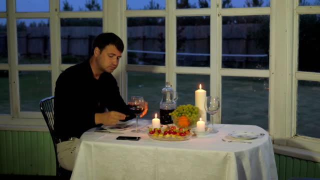 Hombre-sentado-en-la-mesa,-bebiendo-vino-tinto,-comer-canapés,-llamando-al-camarero