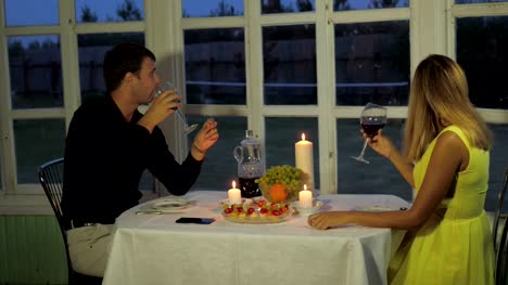 Paar-am-Abend-über-einen-romantischen-Candle-Light-Tisch-auf-der-Veranda,-lustige-reden