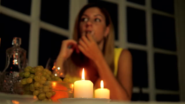 Solitaria-mujer-cenando-en-un-restaurante-de-la-luz-de-las-velas,-bebiendo-vino,-comiendo-fruta