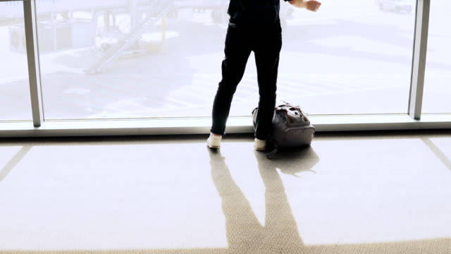 Mujer-con-mochila-camina-a-la-ventana-de-aeropuerto.-Chica-feliz-éxito-pasajero-europeo-con-smartphone-en-terminal.-4K