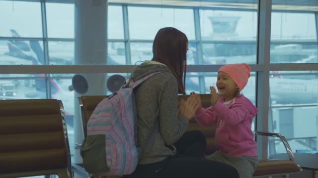 Yound-mother-and-little-cute-daughter-having-fun-at-airport-in-slow-motion.