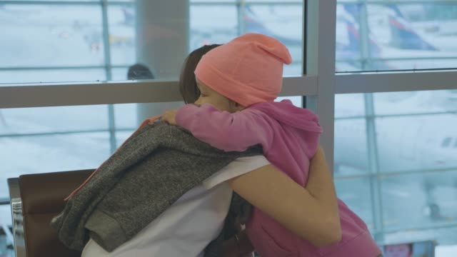 Jungen-Mutter-und-kleine-süße-Tochter-sanft-am-Flughafen-in-Zeitlupe-zu-umarmen.