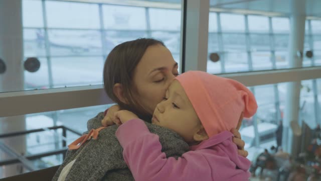 Yound-mother-and-little-cute-daughter-gently-embrace-at-airport-in-slow-motion.