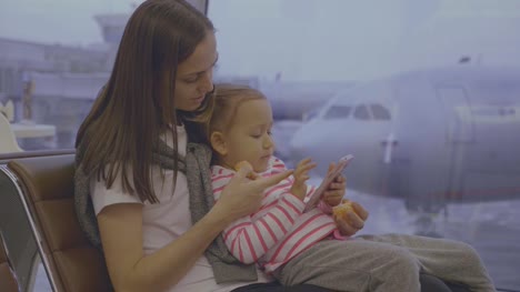 Mother-feeds-her-little-daughter-with-tangerine-at-airport-in-slow-motion