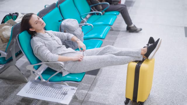 Beautiful-woman-with-short-brunette-hairs-lying-in-a-seats-with-her-legs-on-a-baggage
