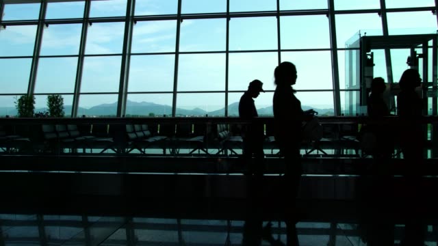 Silhouetten-von-Reisenden-in-einem-geschäftigen-Flughafen-terminal-gegen-Glas-Wand-Fenster