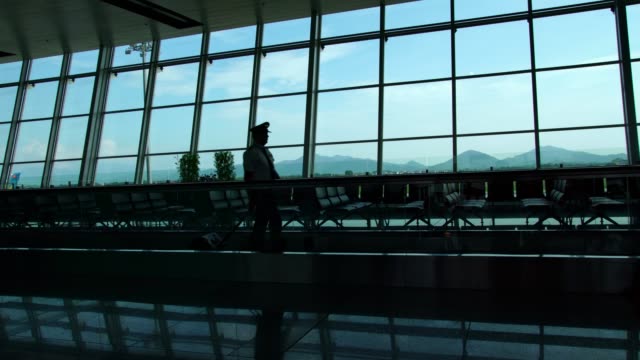 Silhouette-eines-Piloten-zu-Fuß-in-einer-geschäftigen-Flughafen-terminal