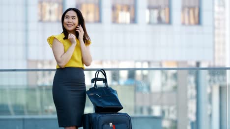 Mujer-de-negocios-asiática-hablando-por-teléfono-móvil-al-aire-libre