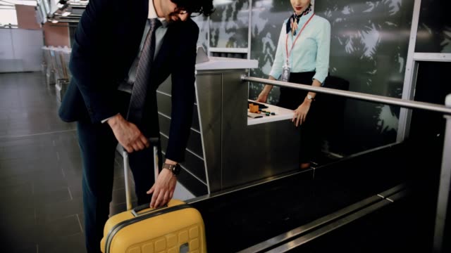 Young-man-weighing-suitcase-and-doing-check-in-at-airport