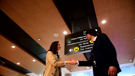Young-businesspeople-greeting-and-shaking-hands-at-airport
