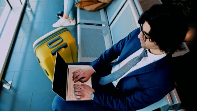Junger-Geschäftsmann-mit-Laptop-während-der-Wartezeit-an-Bord-in-Flugzeug