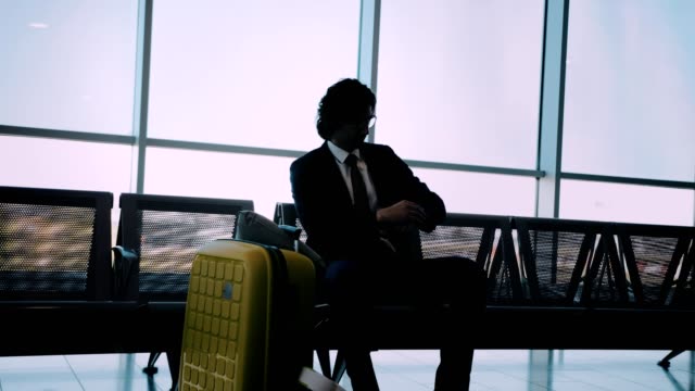 Hombre-de-negocios-sentado-en-el-Banco-y-verificar-el-tiempo-en-el-aeropuerto