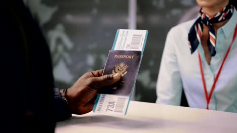 Flight-passenger-holding-passport-and-boarding-pass-at-airline-desk